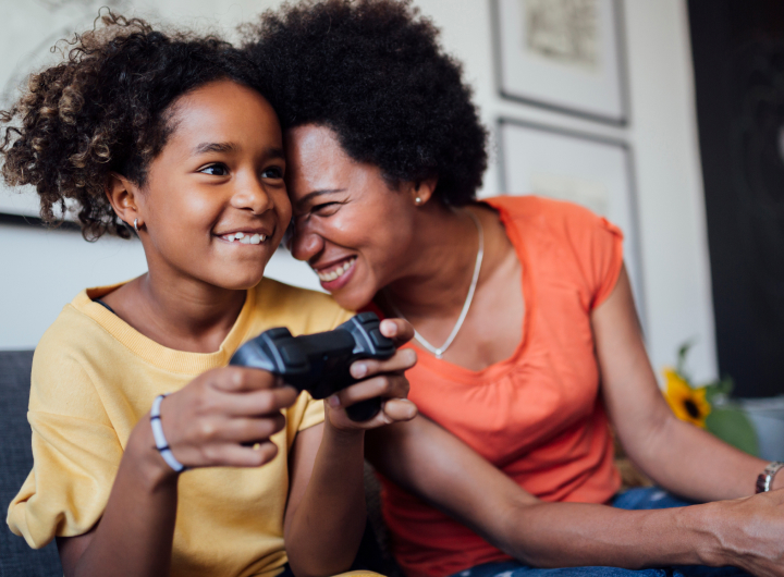 Mum and daughter smile while playing video games, creating healthy screen time habits