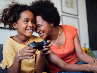 Mum and daughter smile while playing video games, creating healthy screen time habits